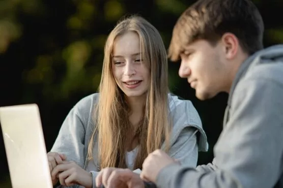 deux etudiants regardent un ordinateur portable dans le parc de l'ESSCA