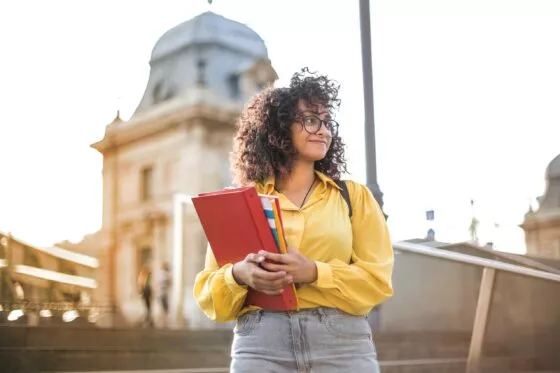 etudiante devant un batiment, tient un porte document