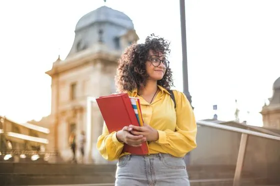 etudiante devant un batiment, tient un porte document