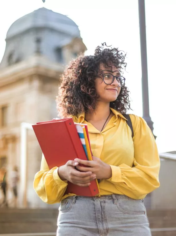 etudiante devant un batiment, tient un porte document