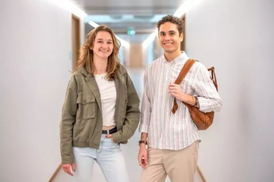un étudiant et une étudiante du campus de l'ESSCA à Bordeaux sont debout dans un couloir et regardent le photographe