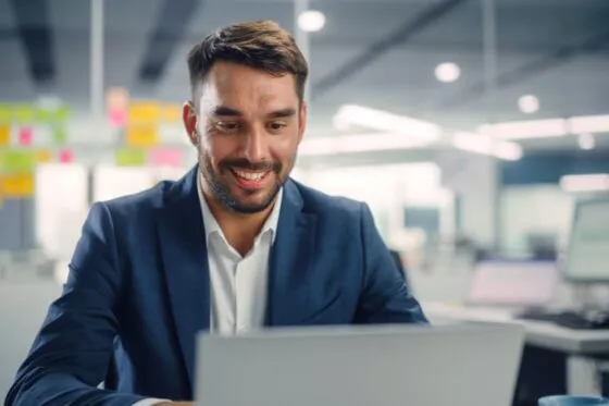 homme souriant assis devant ordinateur portable