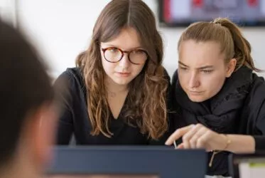 deux étudiantes sont concentrées et travaillent ensemble sur le même ordinateur