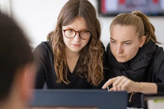 deux étudiantes sont concentrées et travaillent ensemble sur le même ordinateur