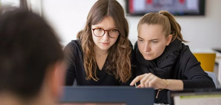 deux étudiantes sont concentrées et travaillent ensemble sur le même ordinateur