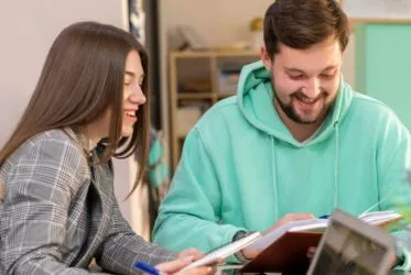 Un étudiant travaille à côté d'une étudiante et lui sourit