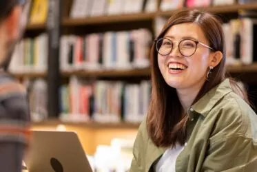 jeune adulte souriante dans une bibliothèque