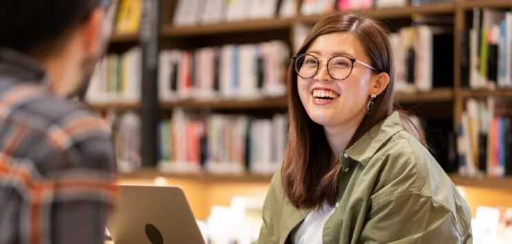 jeune adulte souriante dans une bibliothèque