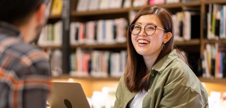 jeune adulte souriante dans une bibliothèque