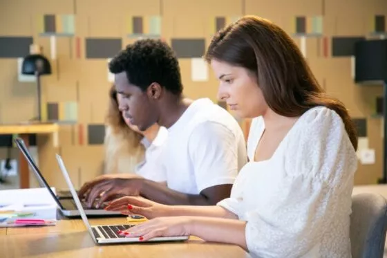 Deux étudiants travaillent dans une bibliothèque avec des ordinateurs